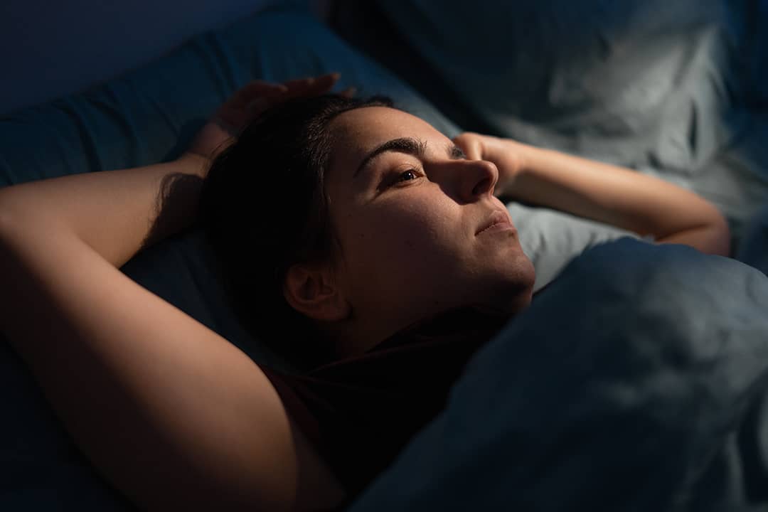A woman drifts into sleep at night.